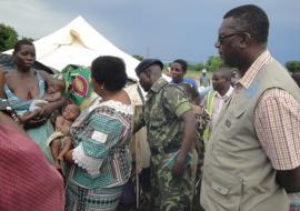 The Honorable Minister Dr Jean Kalilani comforting a twin child listens to the mother of the twins living in one of the camps in Chikwawa districts while Dr Nyarko (far right) in khaki WHO field coat looks on WHO Malawi photo