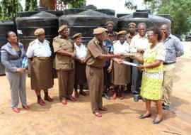 WHO staff, Ms Rose Shija on behalf of the WHO Representative handing over the 4 water tanks to the Segerea prison management witnessed by Dar es Salaam Regional Health Officer and WHO staff.