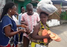 A vaccinator administring polio drops to a child on its mothers back