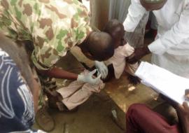 Military personnel vaccinating a child with IPV in Monguno IDP camp of Borno State