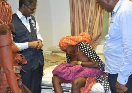 Teenage girl breastfeeding her newborn baby while WHO Representative, Dr Charles Sagoe-Moses and Mr Thomas Shapumbu, Kunene Regional Health Director looks on