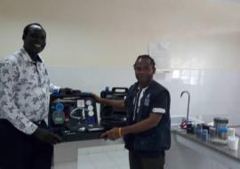 Mr Alex Freeman, handing over the water quality testing kit to the national public health laboratory technician in charge for water quality and safety testing.