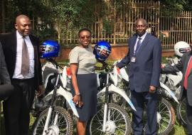 Minister of Health, Dr, Jane Ruth Aceng receives the motorcycles from WHO Acting Rep in Uganda, Dr. Jack Abdoulie as Ministry officials look on