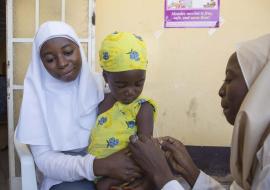 Health workers administering vaccine to an eligible child