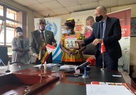 WHO Representative in Uganda, Dr Yonas Tegegn Woldemariam (white shirt) and Mr. Henrik Jespersen, the Head of Cooperation, Royal Danish Embassy in Kampala exchange signed agreements as Hon Hanifa Kawooya (yellow) and Dr Diana Atwine (white and black) look on at the Ministry of Health headquarters in Kampala