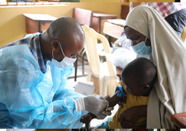 Health worker collecting blood sample for malaria test from one of Zulahatu Ibrahim’s children
