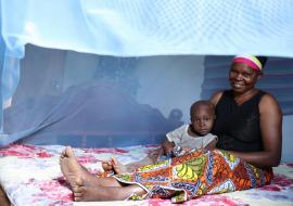 Photo of a mother and child in a treated mosquito bed net