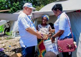 Le Représentant de l’OMS et la déléguée du MSPLS, remettant un kit d’hygiène à une femme du camp des déplacés de Maramvya.