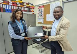 Monica from WHO presents Dr. Duarte of GEPE with a laptop, a contribution to a larger initiative aimed at improving health information