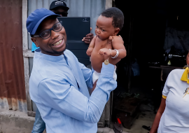 Le Ministre de la Santé Prof Benjamin Hounkpatin tenant un  enfant cible vacciné contre la Polio 