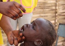 Healthcare workers administering the polio vaccine to a child as part of immunization efforts to protect children from poliovirus.