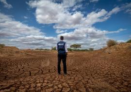Tillen Oduwo from WHO surveys a dried out river in Tula, Tana River County.