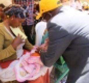 Representative of WHO Dr Thomas  Karengera vaccinating a child