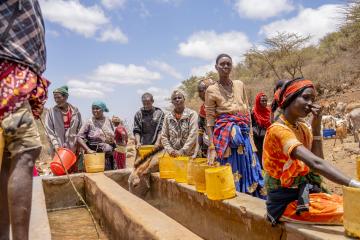 People wait in the midday sun for the water troughs to fill with water at Hula Hula Springs in Marsabit County, Kenya. With the ongoing drought in Marsabit, the spring is the only available water source for the whole community. 