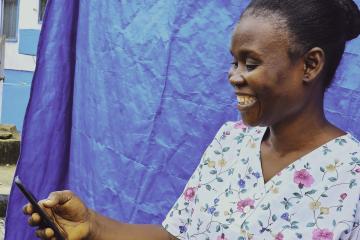 Nyanjikua Foday- Vaccinator at Dupo Road Health centre in Montserrado smiles after receiving a mobile money notification. Nyanjikua Foday- Vaccinator at Dupo Road Health centre in Montserrado smiles after receiving a mobile money notification.