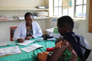 Jovita Atuheire a health worker at Maziba Health Center IV interacting with a patient 