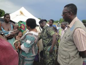 The Honorable Minister Dr Jean Kalilani comforting a twin child listens to the mother of the twins living in one of the camps in Chikwawa districts while Dr Nyarko (far right) in khaki WHO field coat looks on WHO Malawi photo