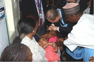 Assisted by the Executive Director of the NPHCDA Dr Ado Muhammad, UN Secretary General administers oral polio vaccine to a child in a WHO supported health facility