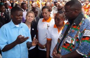 A Health Surveillance Assistant (in blue uniform) explains the procedure of preparing the Rotavirus vaccine to the Vice President as WR second from right looks on