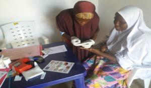 Midwife doing routine malaria Rapid Diagnostic Test (RDT) screening to a pregnant woman as an Ante-Natal Care service in Garba Buzu IDP Camp MdM