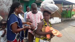 A vaccinator administring polio drops to a child on its mothers back
