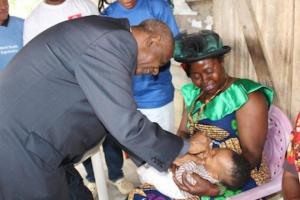 Le Secrétaire d’Etat à la Santé Publique Chargé de la Lutte contre les Epidémies et les Pandémies administre le vaccin polio oral à un nourrisson porté par sa grand-mère.