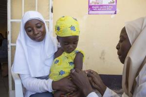 Health workers administering vaccine to an eligible child