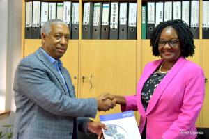 WHO Representative Dr Yonas Tegegn Woldemariam hands the MOU to the Dean of MUSPH Dr Rhoda Wanyenze