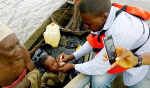 Vaccinator immunizing an eligible child in a boat with OPV during IPDS from his own boat