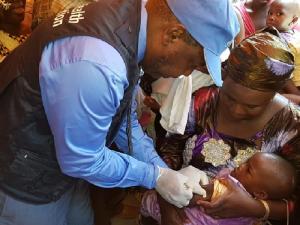 Le Représentant de l'OMS  vaccinant un enfant contre la rougeole à Coyah, Archives OMS 2017