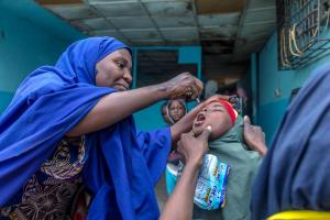 Un vaccinateur fournit à une jeune fille un vaccin oral contre la polio dans l'État de Kano, au Nigeria, en 2020