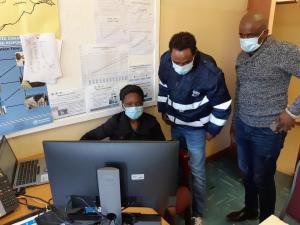 Mr S Kololo – MoHW/HSM (right) and Mr S Feleke – WHO Botswana (centre) observe the M&E Officer of Bobirwa DHMT practicing use of the docking station