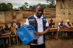 Dans le petit village de Sinkolé, situé dans la région forestière de la Guinée, des dizaines d’hommes et de femmes se rassemblent devant une salle communautaire délabrée, un vendredi matin. Marius Djo, conseiller de l’Organisation mondiale de la Santé (OMS) pour la prévention des abus et de l’exploitation sexuels (PSEA), attend que tout le monde prenne place sur de vieux bancs d’école en bois disposés en demi-cercle, puis il commence son propos par une introduction animée.