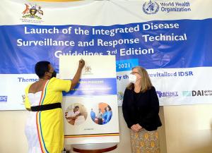 State Minister of Health in Charge of General Duties, Hon Anifa Kawooya signs to launch the IDSR guidelines, while CDC Country Director, Dr Lisa Nelson looks on.