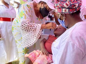 Ms Teopista's son receives his Oral Polio Vaccine drops from the Minister of State in Charge of General Duties Hon. Hanifah Kawooya at the vaccination campaign launch