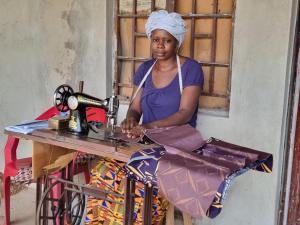 Safiatu using her sewing skills and the machine provided to her by the Mental Health Coalition of Sierra Leone to generate income
