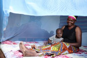 Photo of a mother and child in a treated mosquito bed net