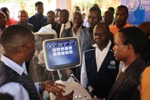 The Kigoma Regional Commissioner receiving a briefing from the regional radiographer, witnessed by the WHO Country Representative, Dr. Yoti and other regional and district authorities.