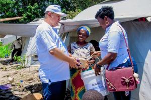 Le Représentant de l’OMS et la déléguée du MSPLS, remettant un kit d’hygiène à une femme du camp des déplacés de Maramvya.