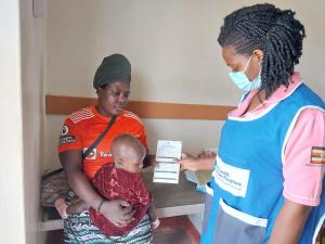A Health worker hands over a child immunization card to a mother