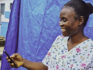 Nyanjikua Foday- Vaccinator at Dupo Road Health centre in Montserrado smiles after receiving a mobile money notification. 