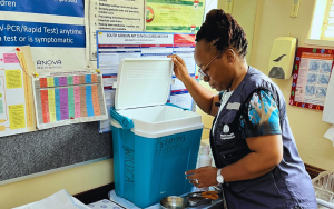 Dr. Simangele Mthethwa, Vaccine-Preventable Disease Surveillance Officer at WHO South Africa,  inspecting or preparing a vaccine cold box—a vital part of maintaining the cold chain required for storing and transporting vaccines at the correct temperature.