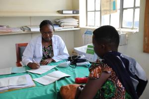 Jovita Atuheire a health worker at Maziba Health Center IV interacting with a patient 
