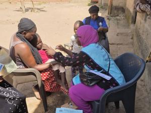 A mother holds her child as a health worker delivers a life-saving measles-rubella vaccine in Cape Point, The Gambia.