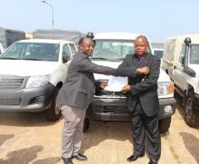 . The WHO Representative, Dr. Alex Gasasira (left) handing over the certificate of transfer of vehicles to the Deputy Minister of Health (Administration), Hon. Mathew T.K. Flomo