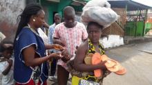  A vaccinator administring polio drops to a child on its mothers back