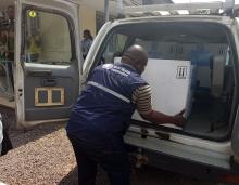 Un agent de l'OMS décharge les cartons contenant les doses de vaccins anti Ebola pour leur conservation dans la chambre froide du Programme Elargi de Vaccination à Kinshasa. OMS/Eugene Kabambi