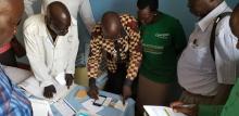The Chief Medical Officer of Juba County, Dr. Justin Nyoma, demonstrates the use of an EWARS mobile phone during a supervisory visit to a health facility