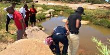 Training workshop participants, in the field, examining stagnant water bodies for malaria mosquito breeding