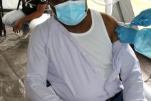 Dr Gervais Folefack, Point focal du Programme des urgences et sécurité sanitaire, OMS RDC reçoit sa première dose de vaccin Astra Zeneca contre le coronavirus, COVID-19 au site des Cliniques Universitaires de Kinshasa (CUK) en marge de la cérémonie du lancement officiel de la campagne de vaccination